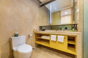 A bathroom with a toilet, a sink with a mirror, and a shelf with towels. - Wanhao Max Hotel - Guangzhou Pazhou (Guangzhou)