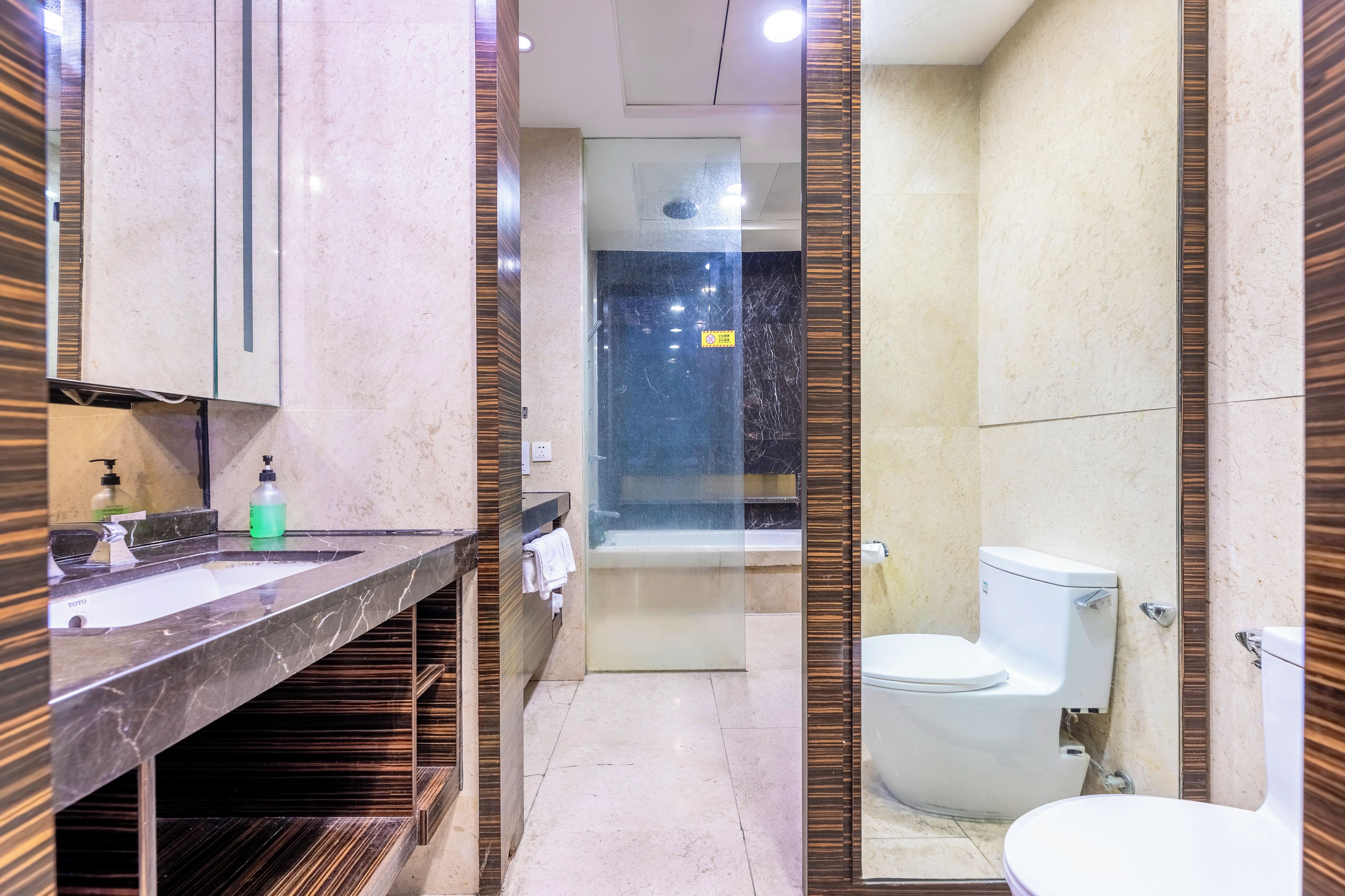 A modern bathroom with a marble sink, a glass-enclosed shower, and a toilet.