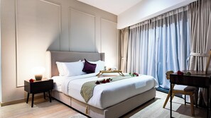 A hotel room with a bed, bedside tables, a desk, and a chair. - Eaton Deluxe Triple Apartment (Kuala Lumpur)