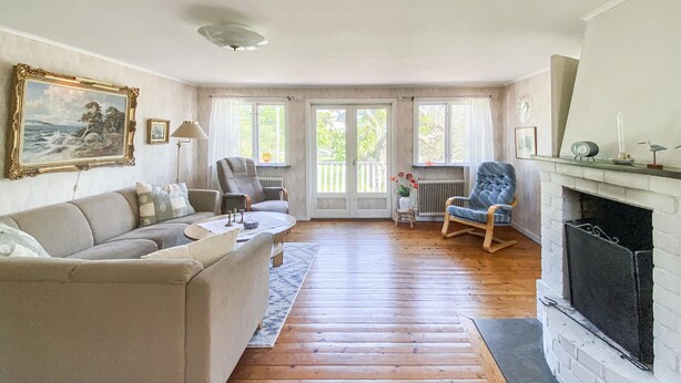 A living room with a sofa, armchairs, a fireplace, and a view through large windows. - Nice home in Köpingsvik with sauna (Köpingsvik)