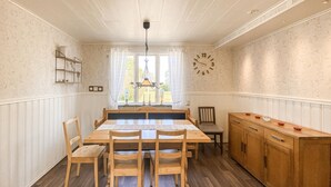 A dining area with a wooden table, chairs, a bench, a wooden cabinet, and a wall clock. - Nice home in Köpingsvik with sauna (Köpingsvik)