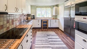 A kitchen with a stove, refrigerator, and wooden cabinets. - Nice home in Köpingsvik with sauna (Köpingsvik)