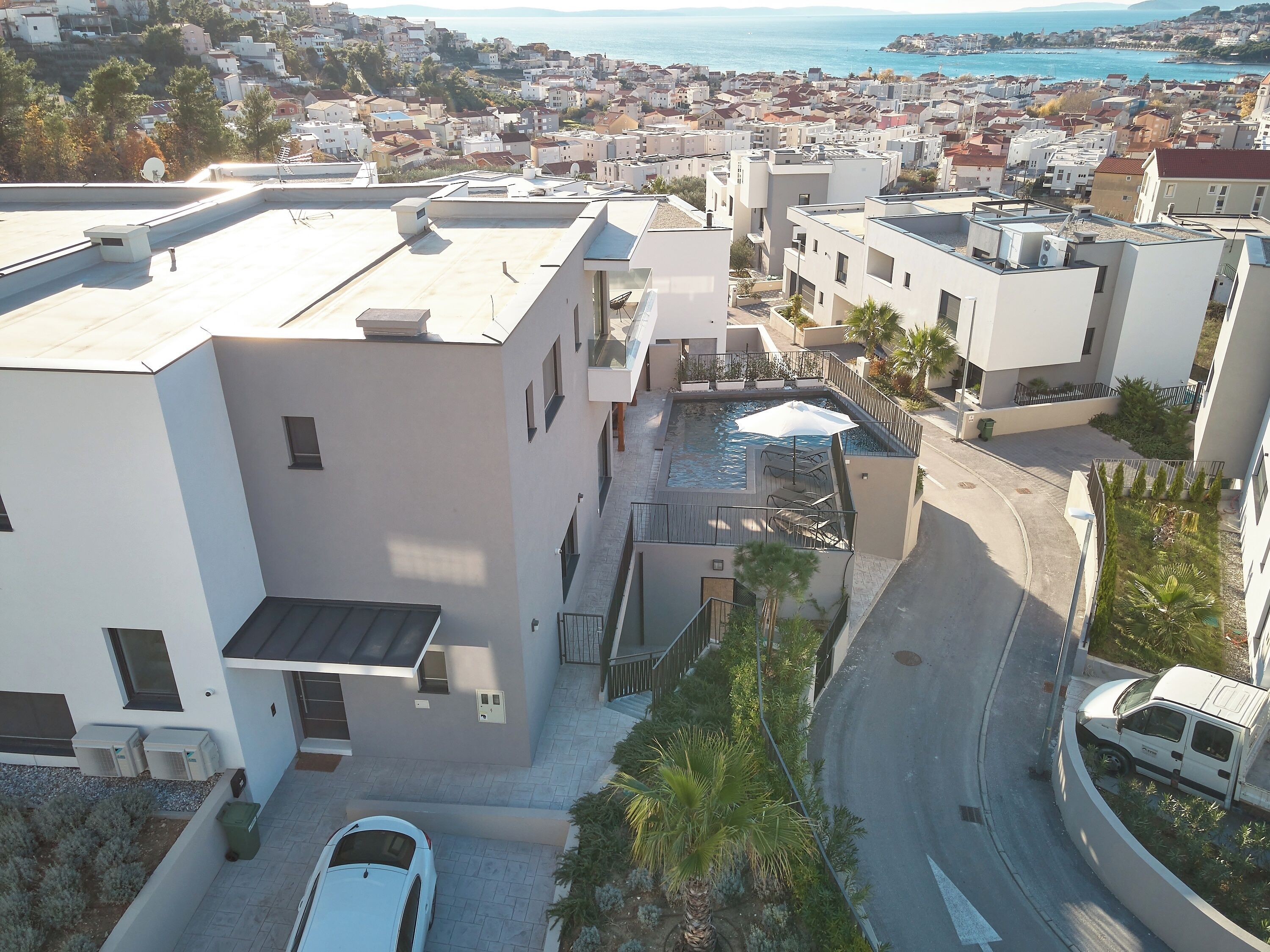 A residential area with modern buildings, a swimming pool, and a road.