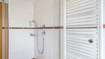 Ein modernes Badezimmer mit weißen Fliesen, einer Glasdusche und einem weißen Handtuchhalter.