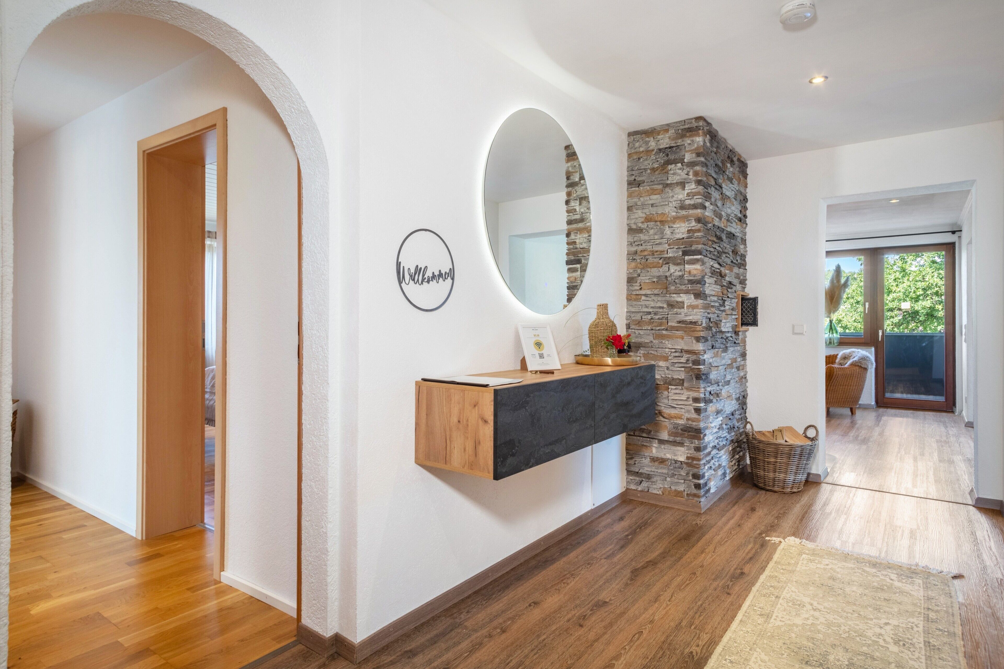 Ein modernes Interieur mit Holzboden, einer Wand aus Naturstein, einem Holzkonsole und einem Spiegel.