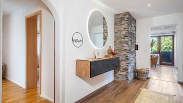Ein modernes Interieur mit Holzboden, einer Wand aus Naturstein, einem Holzkonsole und einem Spiegel.