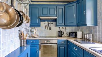 A kitchen with blue cabinets, stainless steel appliances, and a tiled backsplash.