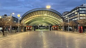 A modern train station with a large, curved roof and multiple ticket gates.