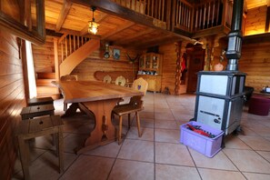 A wooden interior with a dining table, chairs, a cabinet, and a stove. - Chalet Nid d Aigle - 6 personnes - Farquesses (Les Haudères)