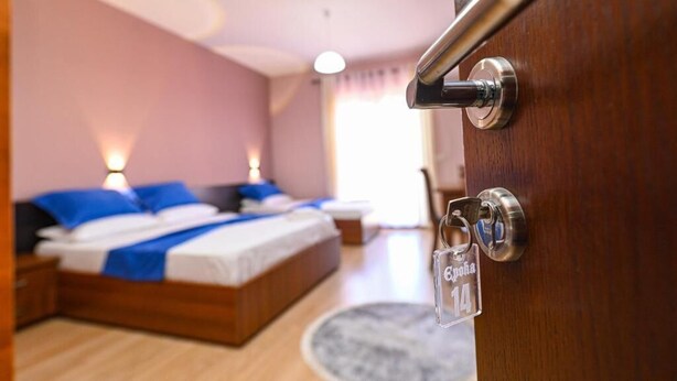 Una habitación de hotel con una cama de madera, una mesita de noche, una lámpara y vistas al exterior.
