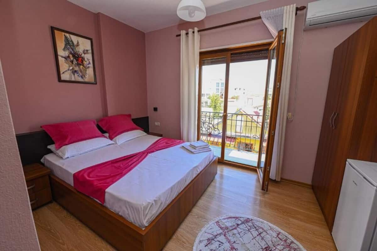 Un dormitorio con cama, mesita de noche, armario y balcón con vistas.