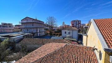 A residential area with terracotta-tiled roofs, a mix of single and multi-story buildings, and a clear blue sky.