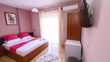 A bedroom with a bed, bedside table, TV, and an air conditioning unit.