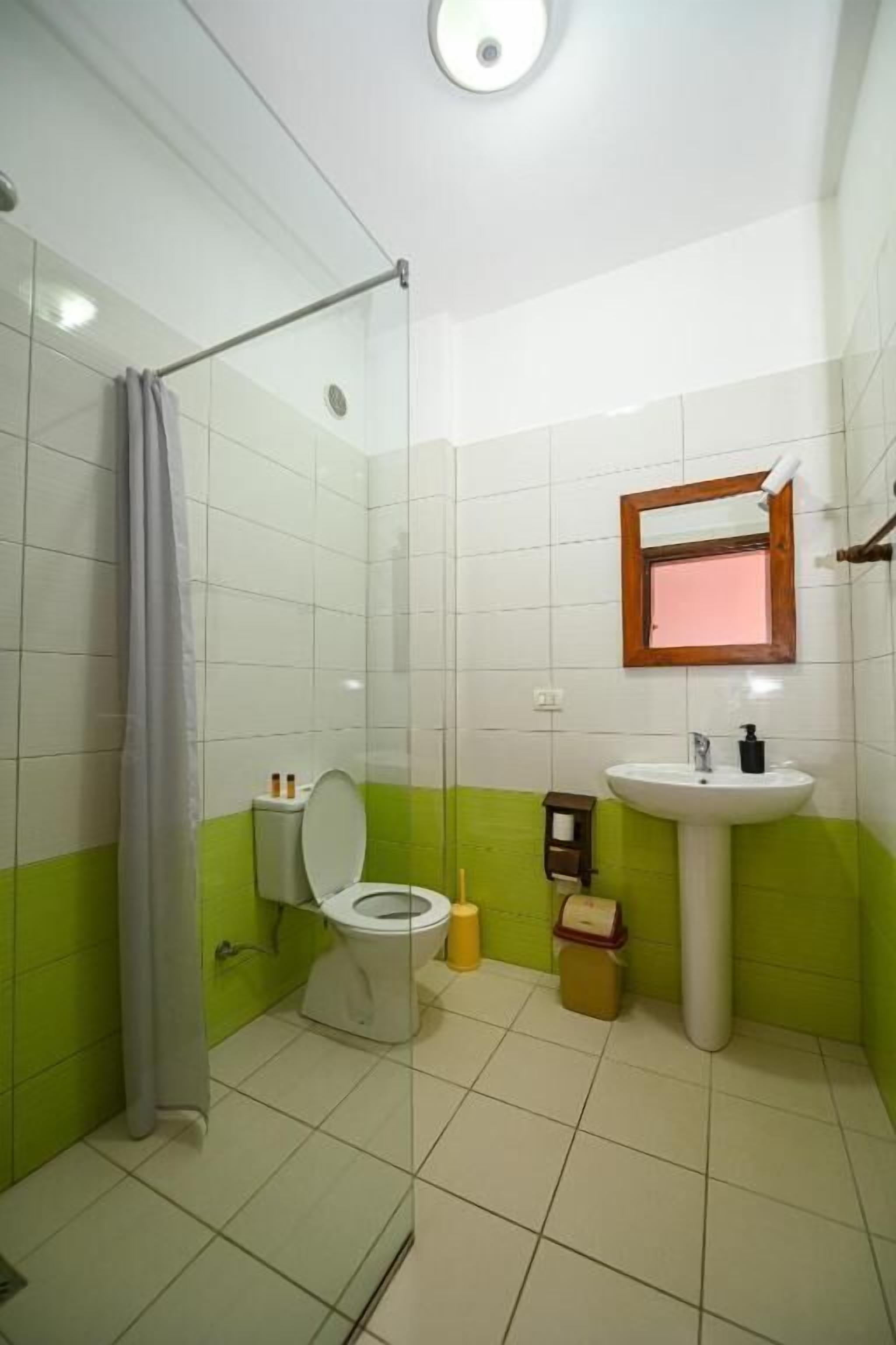 A bathroom with a toilet, sink, and shower area.