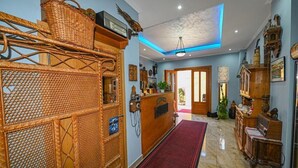 Un área de recepción con un mostrador de mimbre, alfombra roja y un candelabro.