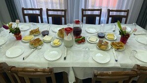 Mesa de comedor lista para seis personas, con platos, cubiertos y diversos alimentos.