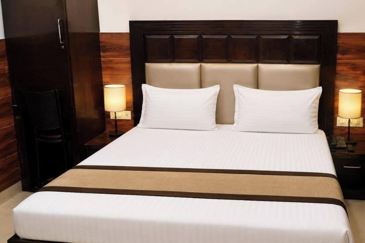 A hotel room with a large bed, two bedside lamps, a TV, and wooden paneling.