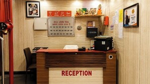 A reception desk with a sign indicating hotel amenities, a SYNTEL machine, and a framed certificate on the wall.