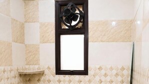 A small bathroom with a toilet, bidet, sink, and a window with a fan.