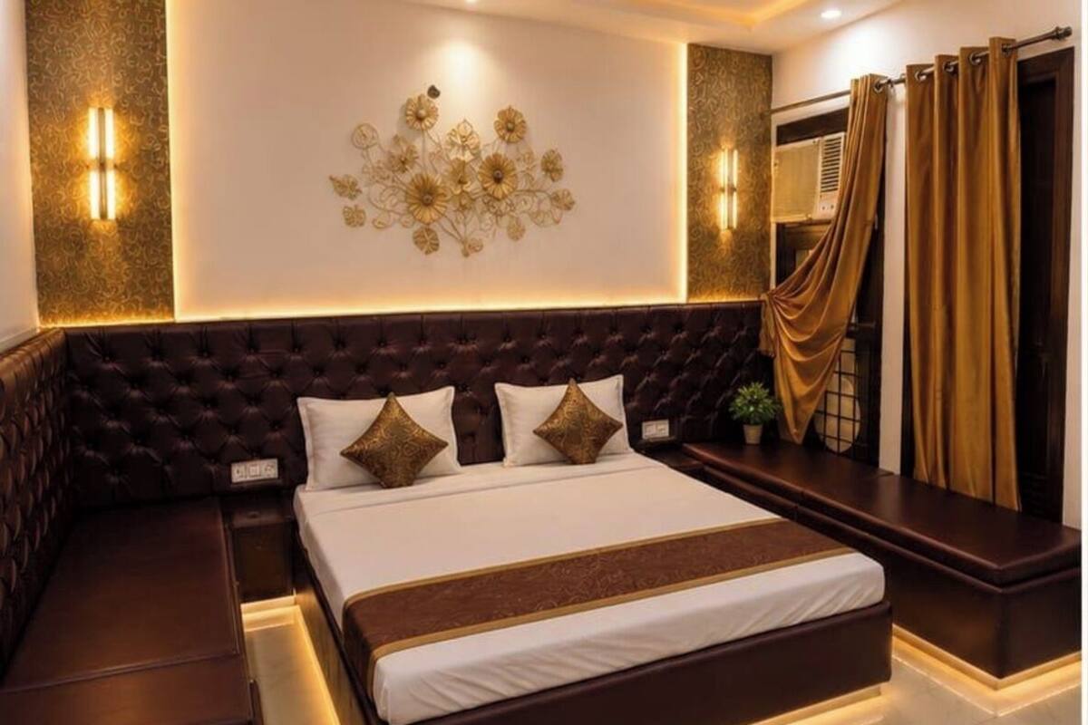 A bedroom with a large bed, a headboard, bedside tables, wall sconces, and a decorative wall piece.