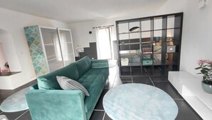 Una sala de estar moderna con un sofá color turquesa, una mesa de centro redonda y un mamparo de vidrio.