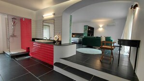 Un baño moderno con tocador rojo, ducha y espejo.