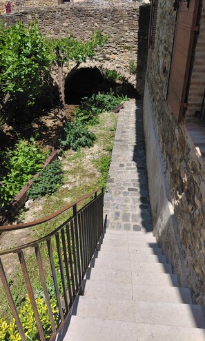 A stone staircase leading to a stone archway, surrounded by greenery and a metal railing. - Charmant appartement de caractère de 90 mq dans ancienne maison en pierres (Saint-Paulet-de-Caisson)