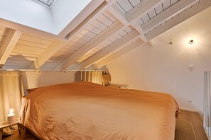 Un dormitorio con una cama grande, tragaluz y ventilador de techo.