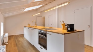 A modern kitchen with a wooden countertop, white cabinets, a built-in oven, and a coffee machine. - 3 bedrooms apartment + private parking in Liege historical area (Liège)