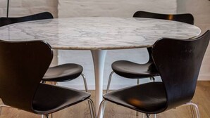 A round table with four black chairs, a teal pendant light, and a white brick wall. - 3 bedrooms apartment + private parking in Liege historical area (Liège)