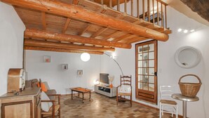 Una sala de estar acogedora con techo de madera, un televisor, una chimenea y un comedor.