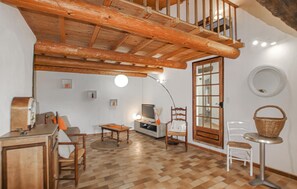 Ein gemütliches Wohnzimmer mit Holzboden, einem Fernseher, einem Kamin und einem Essbereich.