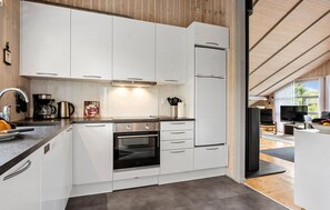 Eine moderne Küche mit weißen Schränken, einem Backofen und einer Kaffeemaschine.