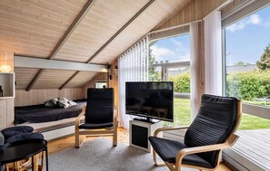 Ein gemütliches Blockhaus mit einem Bett, einem Fernseher und zwei Sesseln.