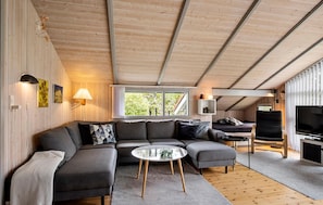 Ein modernes Wohnzimmer mit einer Eckcouch, einem runden Couchtisch und einem Fernseher.