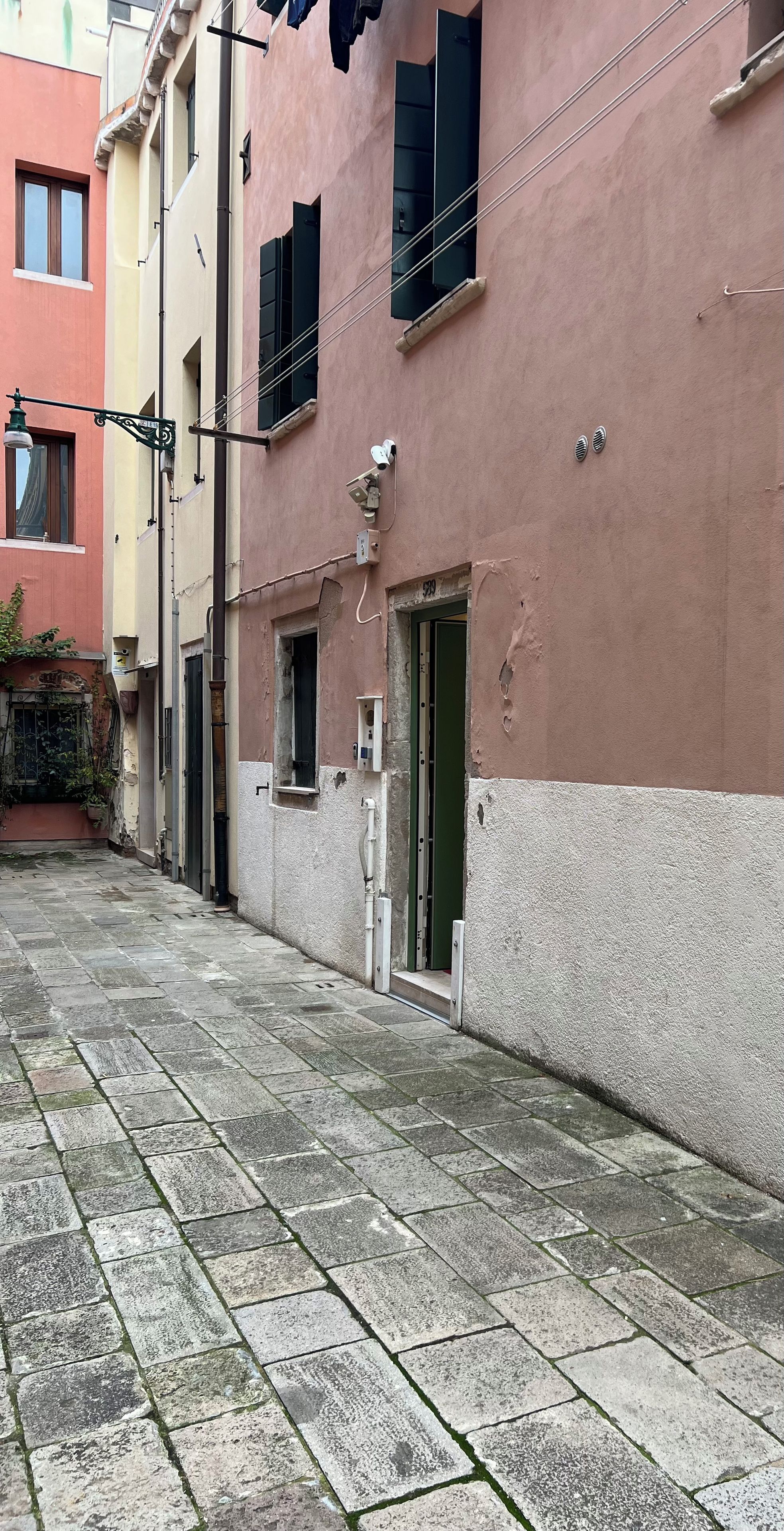 Eine enge Straße mit einem Gebäude, das eine grüne Tür und ein kleines Fenster hat.