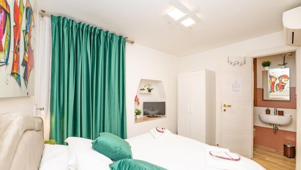 A hotel room with a bed, a TV, a bathroom with a sink, and a door leading to another room. - Isa Sweet Home (Venezia)