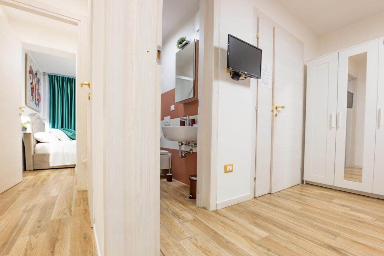 Une chambre d’hôtel avec un plancher en bois, un lit, un téléviseur fixé au mur et une salle de bain équipée d’un lavabo et d’un miroir.
