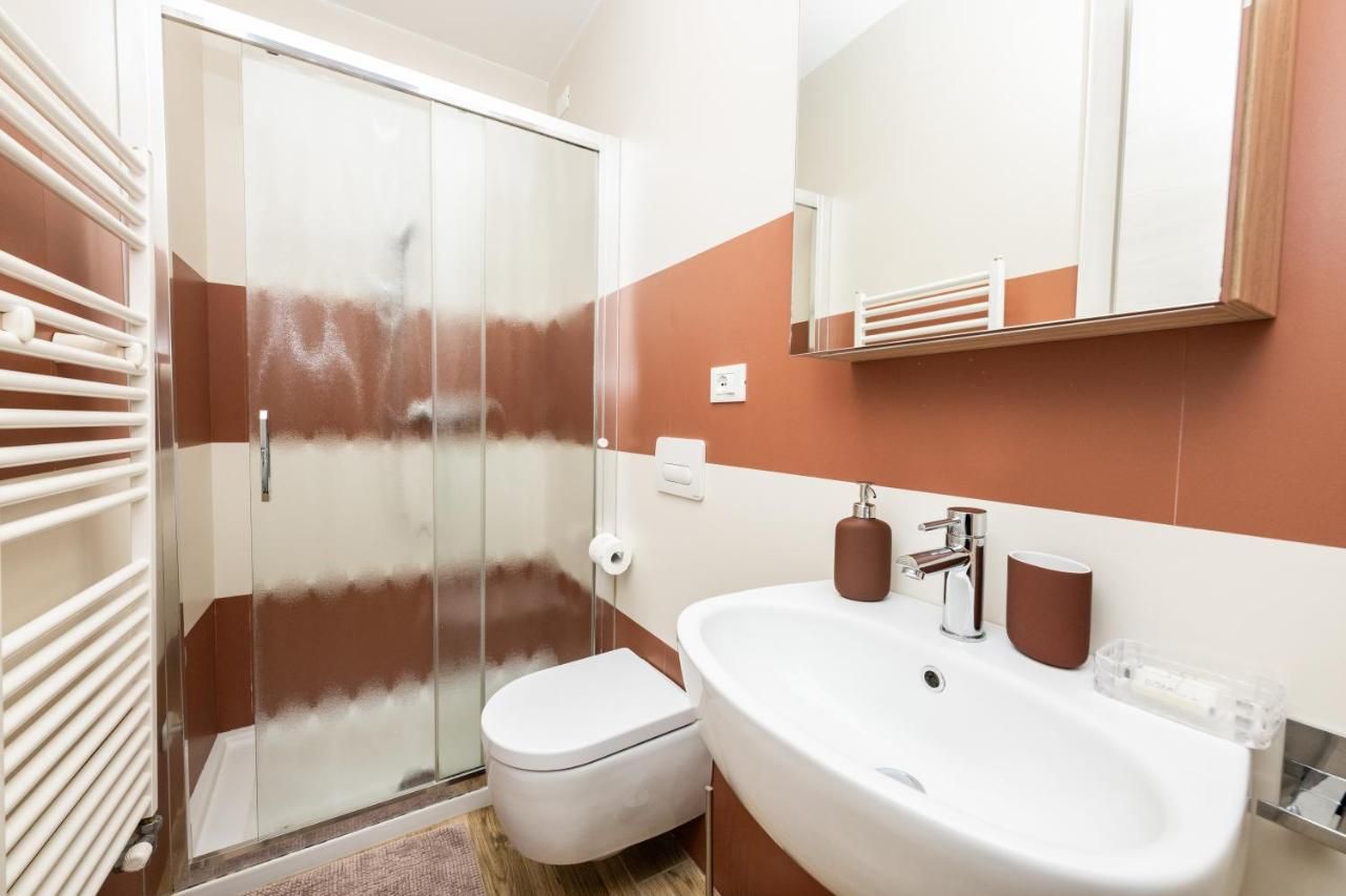 Ein Badezimmer mit Duschkabine, Toilette, Waschbecken mit Spiegel und Handtuchhalter.