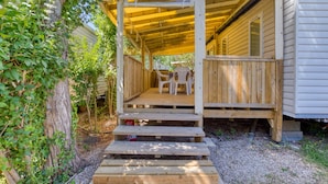 A wooden deck with steps leading to a covered porch area, a small table, and two chairs. - Bungalow with Private Pool, Private Terrace, and Air Conditioning (Agde)