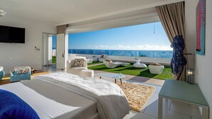 Un dormitorio moderno con una cama grande, televisión y un balcón con vistas.