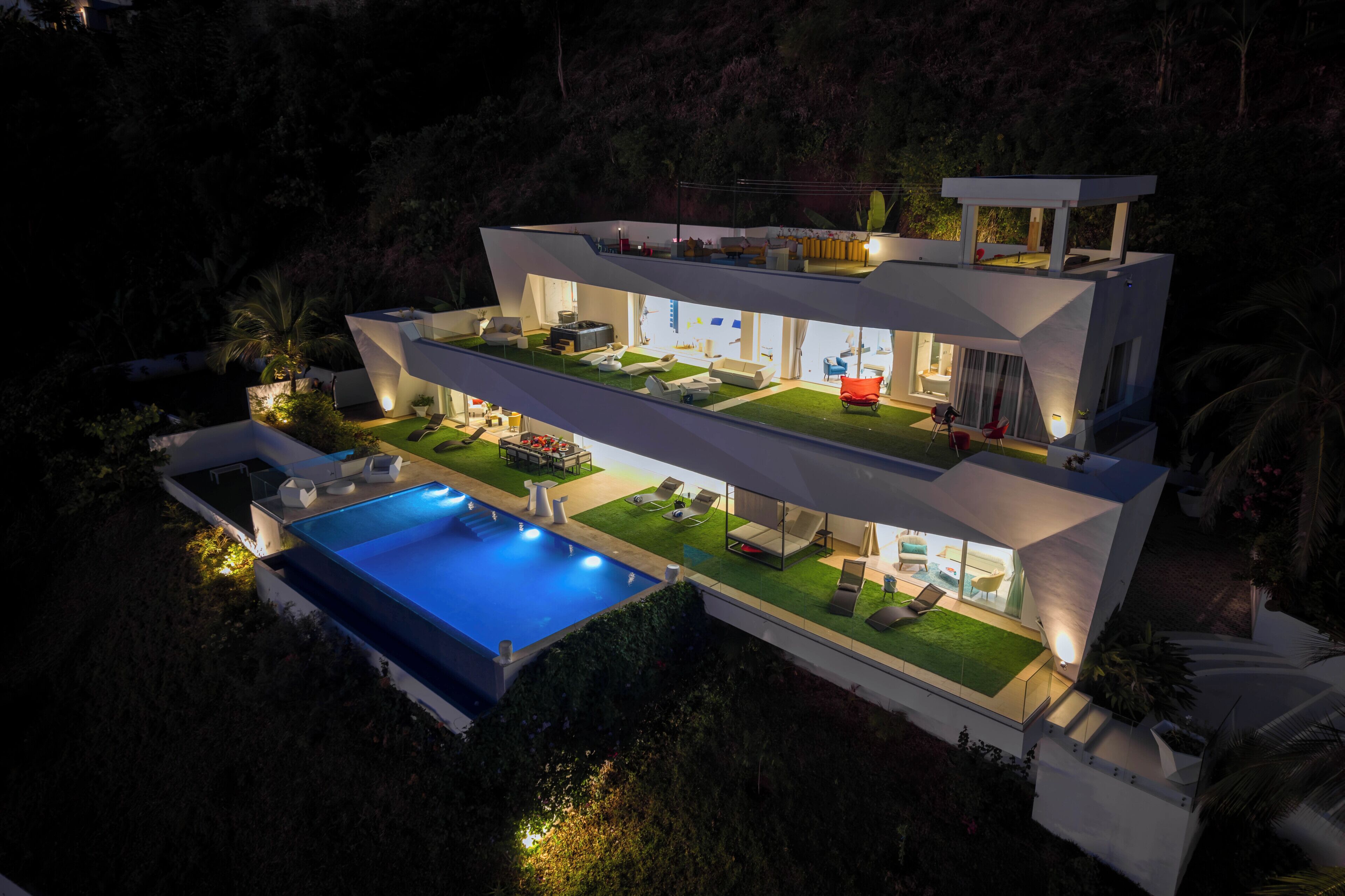 Une maison moderne à plusieurs étages, dotée d’une piscine, d’un espace extérieur aménagé et d’un intérieur bien éclairé.