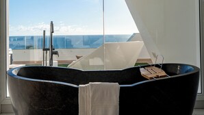 Un baño moderno con una bañera independiente, una toalla y vistas a la ciudad.