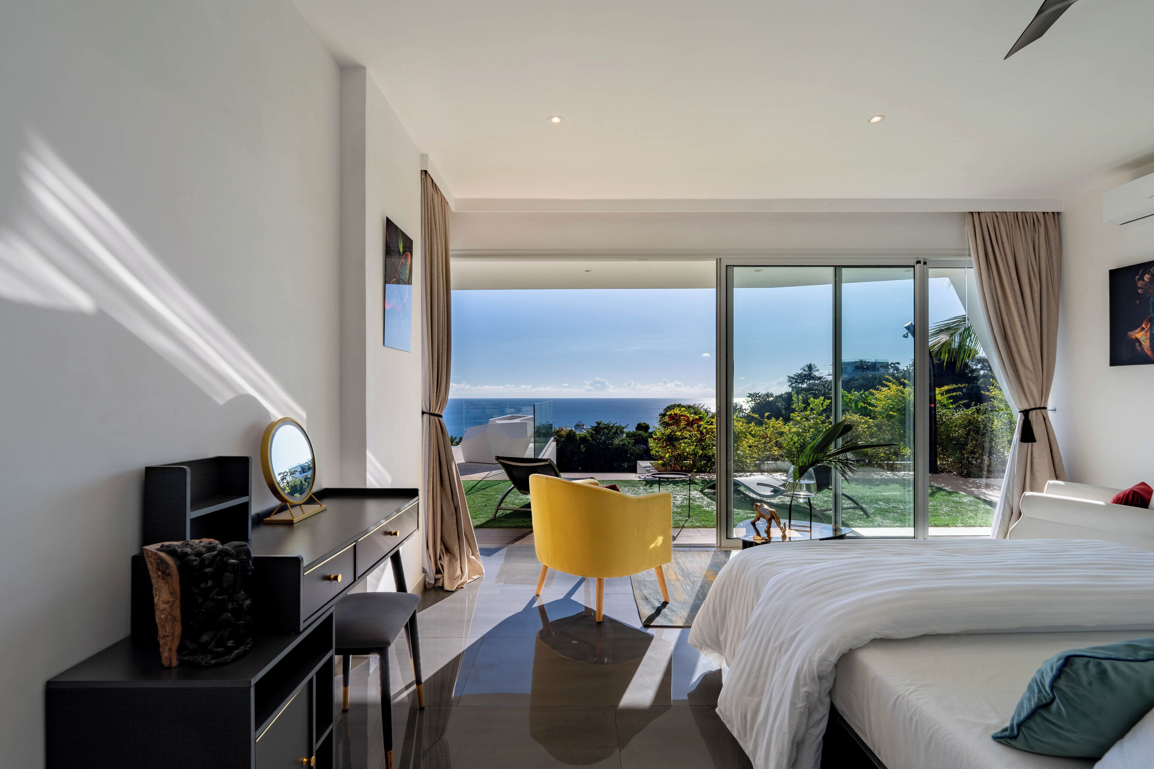 A modern hotel room with a bed, a desk, a chair, and a balcony with a view.
