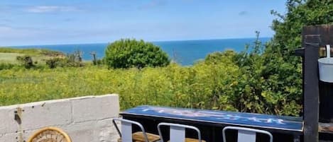A patio with a table and two chairs, overlooking a scenic view of the ocean.
