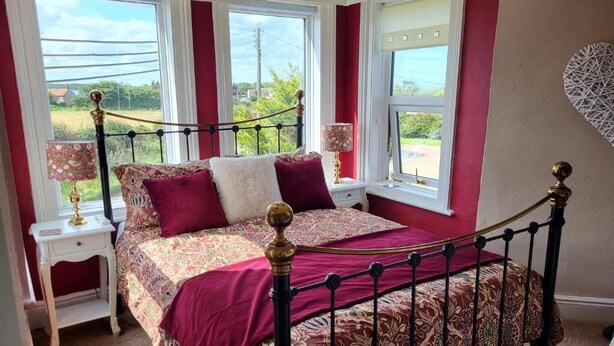 Un dormitorio con una cama, dos mesitas de noche, una ventana con vistas y un adorno decorativo en la pared.