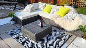 Un patio con un sofá, un tapete estampado y dos plantas en macetas.