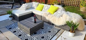 Un patio con un sofá, un tapete estampado y dos plantas en macetas.