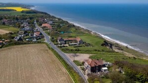 Vista aérea de un pueblo costero con casas, una carretera y campos.