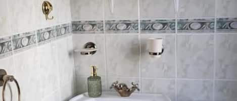 A bathroom with a pedestal sink, toilet, and a shelf with decorative items.